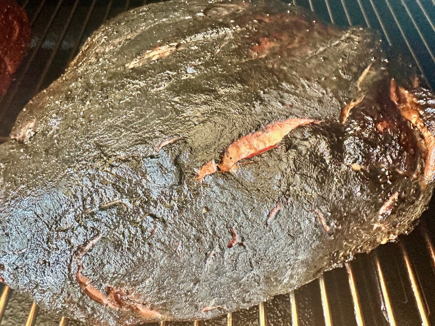 A brisket deep in the smoke, bark setting on the grate